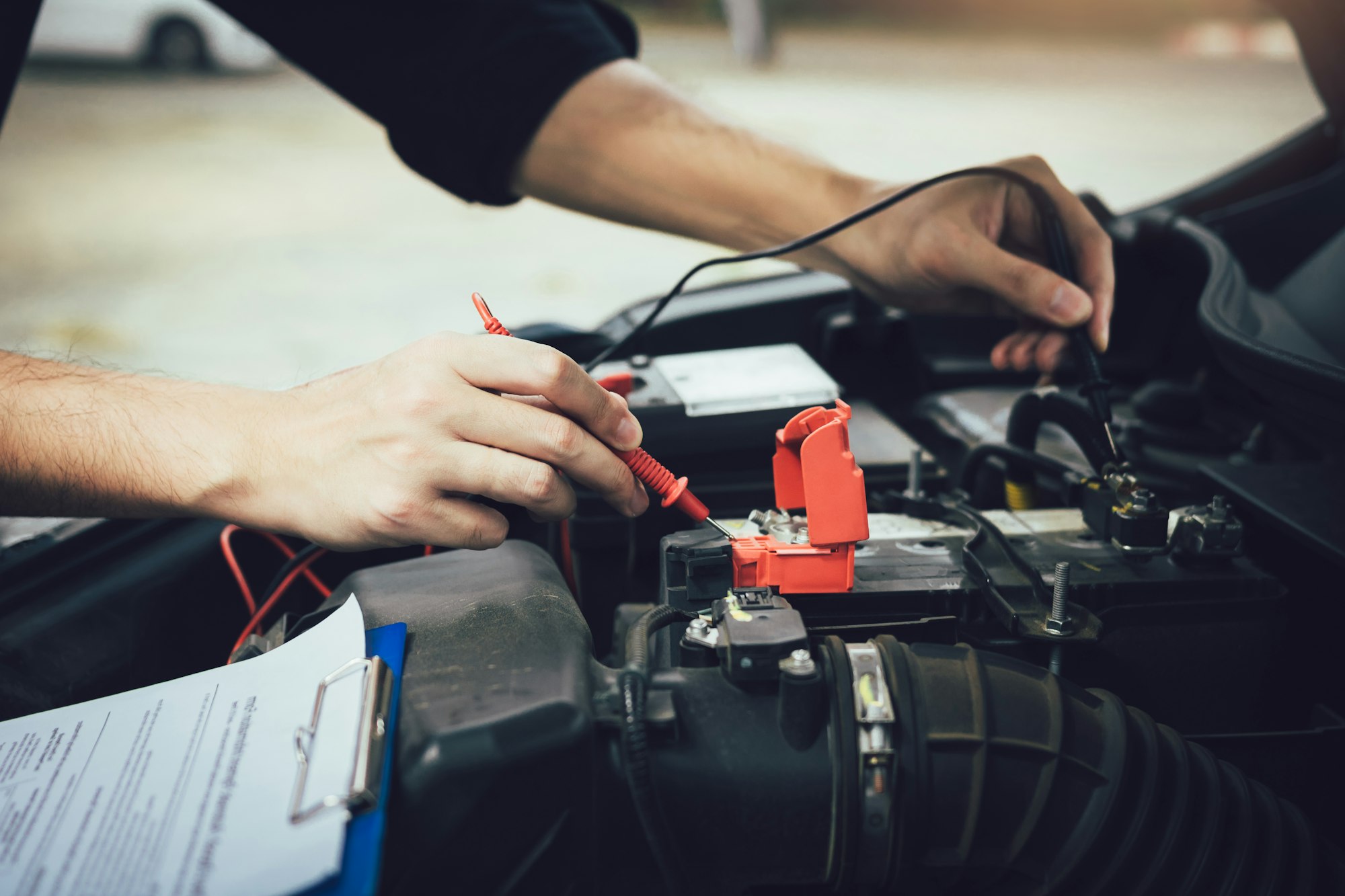 Car mechanic is using the car battery meter to measure various values and analyze it.